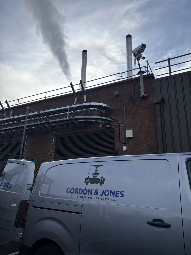 Gordon & Jones Industrial Boiler Services van parked outside an industrial boiler house with flues venting steam